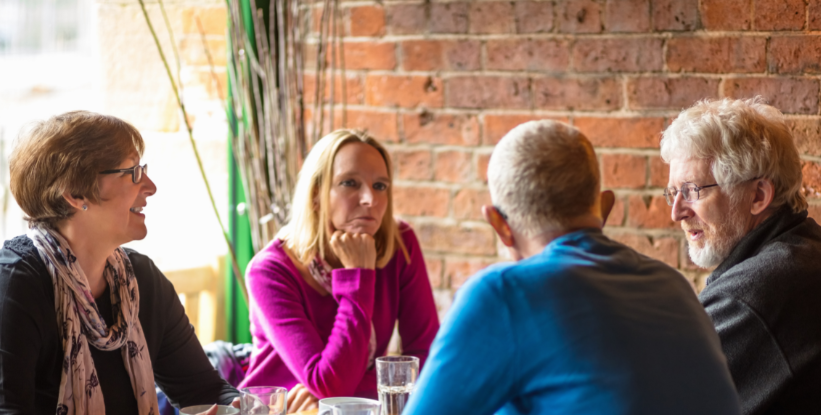 Two men and two women are chatting at a table