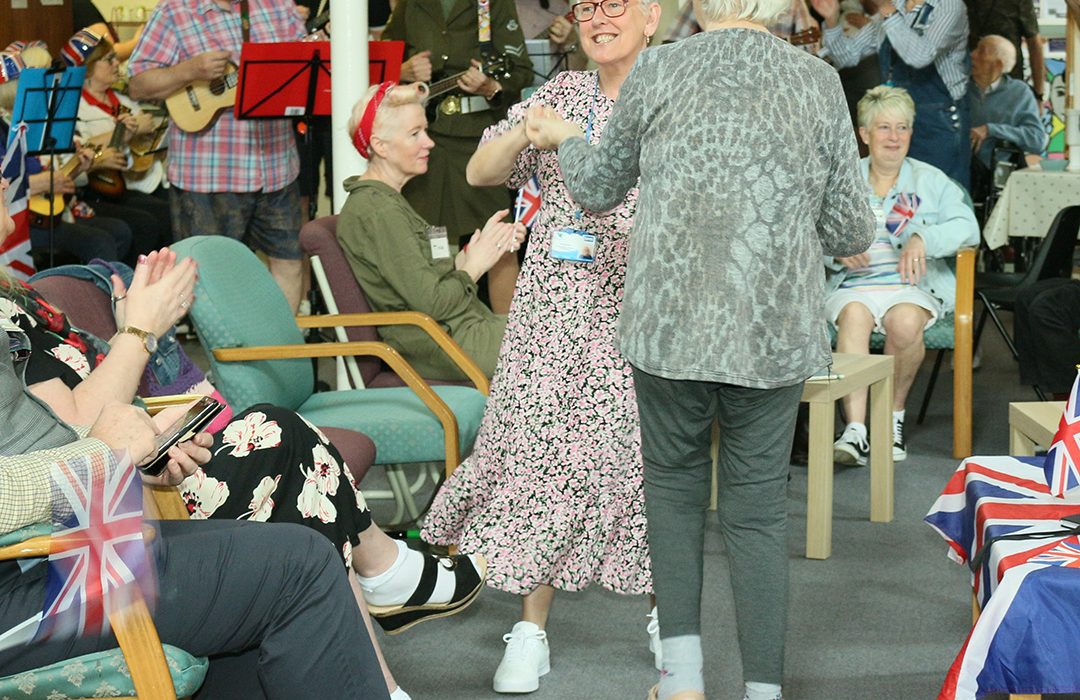 A VE Day celebration, two ladies are dancing while others look on